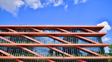 Gökyüzü arka planında cam cepheli modern ofis binası. Ofis binasının şeffaf cam duvarı.