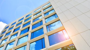 Gökyüzü arka planında cam cepheli modern ofis binası. Ofis binasının şeffaf cam duvarı.