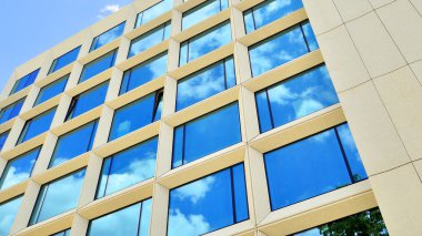 Gökyüzü arka planında cam cepheli modern ofis binası. Ofis binasının şeffaf cam duvarı.