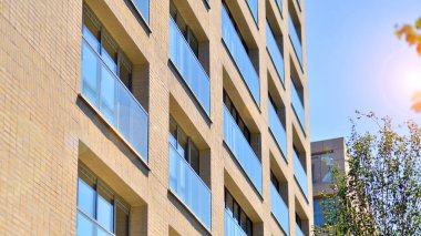 Yeşil bölgedeki yeni apartman blokları. Eko apartman binası enerji ve temiz hava tasarrufu sağlıyor. Yeşil ağaç ve yeni apartman. Doğanın ve modernliğin ahengi.