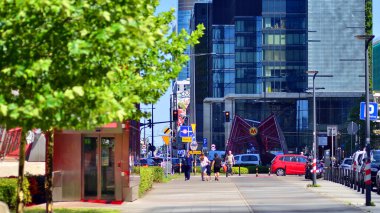 Varşova, Polonya. 31 Temmuz 2024. Güneşli bir yaz gününde kalabalık bir şehir caddesinde yürüyen insanlar. İnsanları modern binaların arka planına karşı görüyorlar. Şehir hayatı, şehir manzarası.