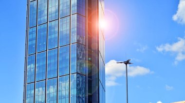 Binanın şeffaf yüzüyle cam bina ve mavi gökyüzü. Yapısal cam duvar mavi gökyüzünü yansıtıyor. Soyut modern mimari parçası. Çağdaş mimari arka plan.