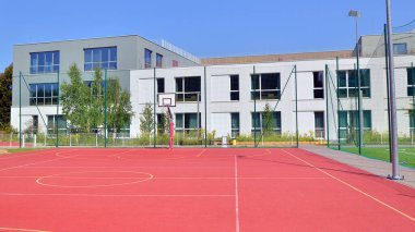 Okul bahçesi, basketbol sahası ve okul binası güneşli bir günde.. 
