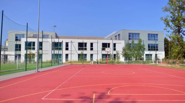 Okul bahçesi, basketbol sahası ve okul binası güneşli bir günde.. 