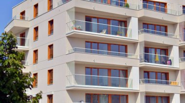 Bir sürü balkon ve penceresi olan bir apartman. Bina ağaçlarla çevrili ve bir sürü yeşilliği var. Binaların çevresi yeşildir. Ekolojik konutlar.