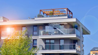 Bir sürü balkon ve penceresi olan bir apartman. Bina ağaçlarla çevrili ve bir sürü yeşilliği var. Binaların çevresi yeşildir. Ekolojik konutlar.