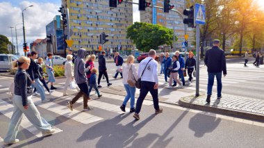 Szczecin, Polonya. 14 Eylül 2024. Şehir merkezinde güneşli bir günde ve büyük bir şehrin caddesinde. Farklı yaşlarda insanlar karşıdan karşıya geçiyor. Şehir sakinleri ve modern binaların olduğu bir cadde manzarası.