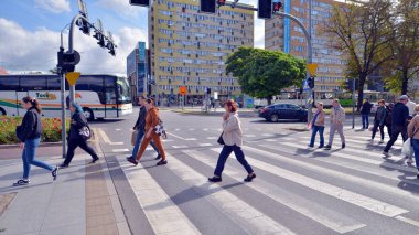 Szczecin, Polonya. 14 Eylül 2024. Şehir merkezinde güneşli bir günde ve büyük bir şehrin caddesinde. Farklı yaşlarda insanlar karşıdan karşıya geçiyor. Şehir sakinleri ve modern binaların olduğu bir cadde manzarası.