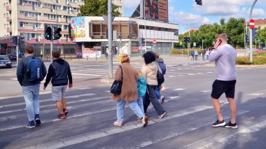 Szczecin, Polonya. 14 Eylül 2024. Şehir merkezinde güneşli bir günde ve büyük bir şehrin caddesinde. Farklı yaşlarda insanlar karşıdan karşıya geçiyor. Şehir sakinleri ve modern binaların olduğu bir cadde manzarası.