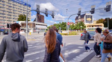 Szczecin, Polonya. 14 Eylül 2024. Şehir merkezinde güneşli bir günde ve büyük bir şehrin caddesinde. Farklı yaşlarda insanlar karşıdan karşıya geçiyor. Şehir sakinleri ve modern binaların olduğu bir cadde manzarası.