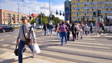 Szczecin, Polonya. 14 Eylül 2024. Şehir merkezinde güneşli bir günde ve büyük bir şehrin caddesinde. Farklı yaşlarda insanlar karşıdan karşıya geçiyor. Şehir sakinleri ve modern binaların olduğu bir cadde manzarası.