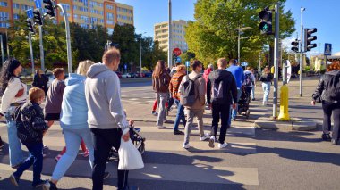 Szczecin, Polonya. 14 Eylül 2024. Şehir merkezinde güneşli bir günde ve büyük bir şehrin caddesinde. Farklı yaşlarda insanlar karşıdan karşıya geçiyor. Şehir sakinleri ve modern binaların olduğu bir cadde manzarası.