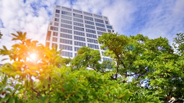 Çok katlı, modern bir apartmanın dış cephesi, pencereleri ve balkonları. Çevre dostu, yeşilliklerle dolu bir şehir..