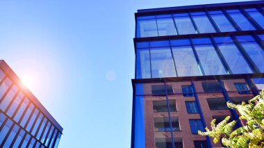 Mavi gökyüzüne karşı birçok penceresi olan modern binanın dış görünüşü, düşük açı görünümü.