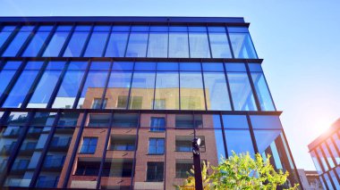 Mavi gökyüzüne karşı birçok penceresi olan modern binanın dış görünüşü, düşük açı görünümü.