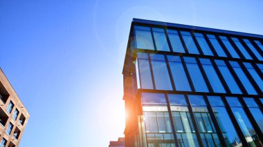 Mavi gökyüzüne karşı birçok penceresi olan modern binanın dış görünüşü, düşük açı görünümü.