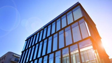 Mavi gökyüzüne karşı birçok penceresi olan modern binanın dış görünüşü, düşük açı görünümü.