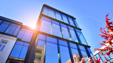 Mavi gökyüzüne karşı birçok penceresi olan modern binanın dış görünüşü, düşük açı görünümü.