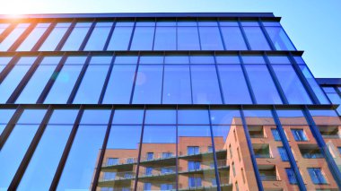 Mavi gökyüzüne karşı birçok penceresi olan modern binanın dış görünüşü, düşük açı görünümü.