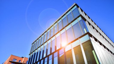 Mavi gökyüzüne karşı birçok penceresi olan modern binanın dış görünüşü, düşük açı görünümü.
