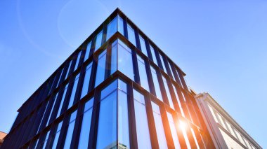 Mavi gökyüzüne karşı birçok penceresi olan modern binanın dış görünüşü, düşük açı görünümü.