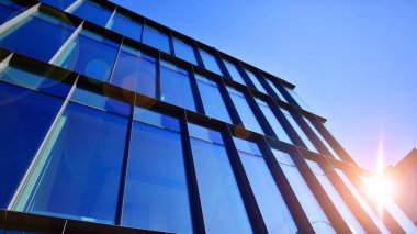 Mavi gökyüzüne karşı birçok penceresi olan modern binanın dış görünüşü, düşük açı görünümü.