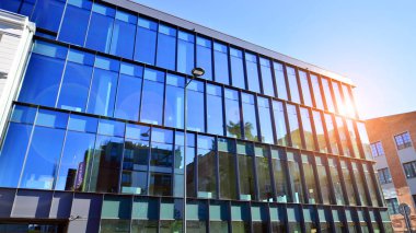 Mavi gökyüzüne karşı birçok penceresi olan modern binanın dış görünüşü, düşük açı görünümü.