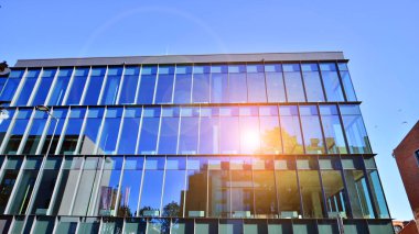 Mavi gökyüzüne karşı birçok penceresi olan modern binanın dış görünüşü, düşük açı görünümü.