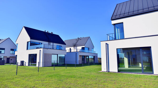 Новый элегантный современный односемейный дом. Разрушенные семейные дома в недавно застроенном жилом комплексе. Фасад современного дома с белыми стенами. Концепция недвижимости, европейский стиль.  