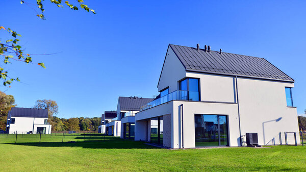 Новый элегантный современный односемейный дом. Разрушенные семейные дома в недавно застроенном жилом комплексе. Фасад современного дома с белыми стенами. Концепция недвижимости, европейский стиль.  