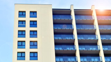 Beyaz, modern, yüksek katlı apartman binası, mavi gökyüzüne karşı dik dur, parlak, açısal tasarımlarla yenilikçi şehir mimarisini örnek al..