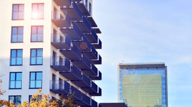 Beyaz, modern, yüksek katlı apartman binası, mavi gökyüzüne karşı dik dur, parlak, açısal tasarımlarla yenilikçi şehir mimarisini örnek al..