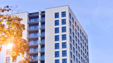 Yeşil yerleşim bölgesinde yeni daireleri olan modern bir yerleşim yeri. Çevre mimarisi. Sarı ağaç ve yeni apartman. Doğanın ve modernliğin ahengi.