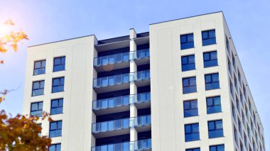 Yeşil yerleşim bölgesinde yeni daireleri olan modern bir yerleşim yeri. Çevre mimarisi. Sarı ağaç ve yeni apartman. Doğanın ve modernliğin ahengi.
