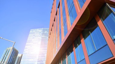 Arka planda mavi gökyüzü olan modern yüksek katlı ofis binalarına bakıyorum..