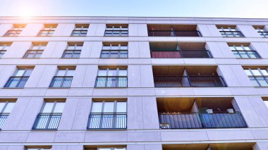 Mavi gökyüzü olan güneşli bir günde modern apartman binaları. Modern bir apartmanın ön cephesi. Güneş ışığıyla kaplı cam yüzey..