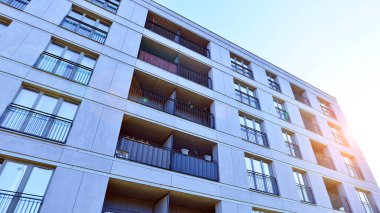 Mavi gökyüzü olan güneşli bir günde modern apartman binaları. Modern bir apartmanın ön cephesi. Güneş ışığıyla kaplı cam yüzey..