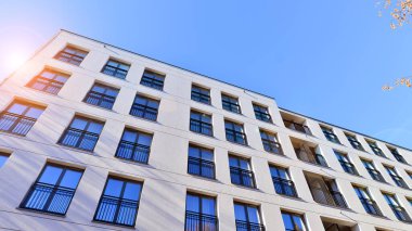 Mavi gökyüzü olan güneşli bir günde modern apartman binaları. Modern bir apartmanın ön cephesi. Güneş ışığıyla kaplı cam yüzey..