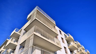 Mavi gökyüzü olan güneşli bir günde modern apartman binaları. Modern bir apartmanın ön cephesi. Gündüz gözüyle çağdaş yerleşim yerinin dış tarafında.. 