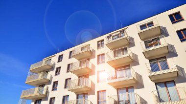 Mavi gökyüzü olan güneşli bir günde modern apartman binaları. Modern bir apartmanın ön cephesi. Gündüz gözüyle çağdaş yerleşim yerinin dış tarafında.. 