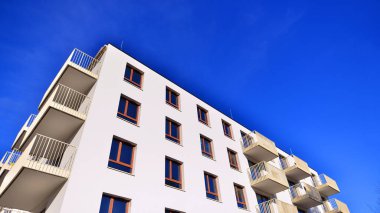 Mavi gökyüzü olan güneşli bir günde modern apartman binaları. Modern bir apartmanın ön cephesi. Gündüz gözüyle çağdaş yerleşim yerinin dış tarafında.. 