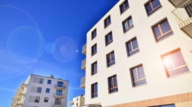 Mavi gökyüzü olan güneşli bir günde modern apartman binaları. Modern bir apartmanın ön cephesi. Gündüz gözüyle çağdaş yerleşim yerinin dış tarafında.. 