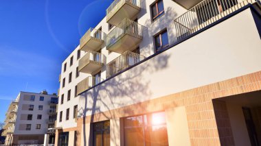 Mavi gökyüzü olan güneşli bir günde modern apartman binaları. Modern bir apartmanın ön cephesi. Gündüz gözüyle çağdaş yerleşim yerinin dış tarafında.. 