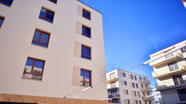 Mavi gökyüzü olan güneşli bir günde modern apartman binaları. Modern bir apartmanın ön cephesi. Gündüz gözüyle çağdaş yerleşim yerinin dış tarafında.. 