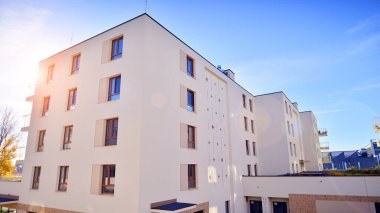 Mavi gökyüzü olan güneşli bir günde modern apartman binaları. Modern bir apartmanın ön cephesi. Gündüz gözüyle çağdaş yerleşim yerinin dış tarafında.. 