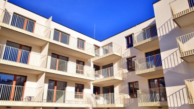 Mavi gökyüzü olan güneşli bir günde modern apartman binaları. Modern bir apartmanın ön cephesi. Gündüz gözüyle çağdaş yerleşim yerinin dış tarafında.. 