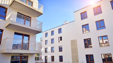 Mavi gökyüzü olan güneşli bir günde modern apartman binaları. Modern bir apartmanın ön cephesi. Gündüz gözüyle çağdaş yerleşim yerinin dış tarafında.. 