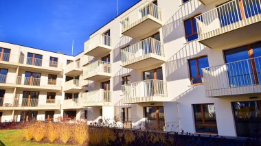 Mavi gökyüzü olan güneşli bir günde modern apartman binaları. Modern bir apartmanın ön cephesi. Gündüz gözüyle çağdaş yerleşim yerinin dış tarafında.. 