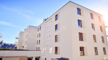 Mavi gökyüzü olan güneşli bir günde modern apartman binaları. Modern bir apartmanın ön cephesi. Gündüz gözüyle çağdaş yerleşim yerinin dış tarafında.. 