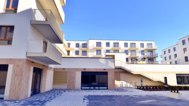 Mavi gökyüzü olan güneşli bir günde modern apartman binaları. Modern bir apartmanın ön cephesi. Gündüz gözüyle çağdaş yerleşim yerinin dış tarafında.. 